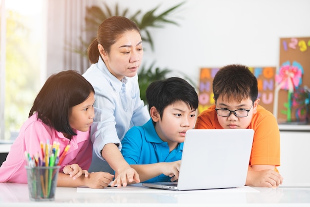 teacher-cute-asian-children-using-laptop-computer-together_38045-35